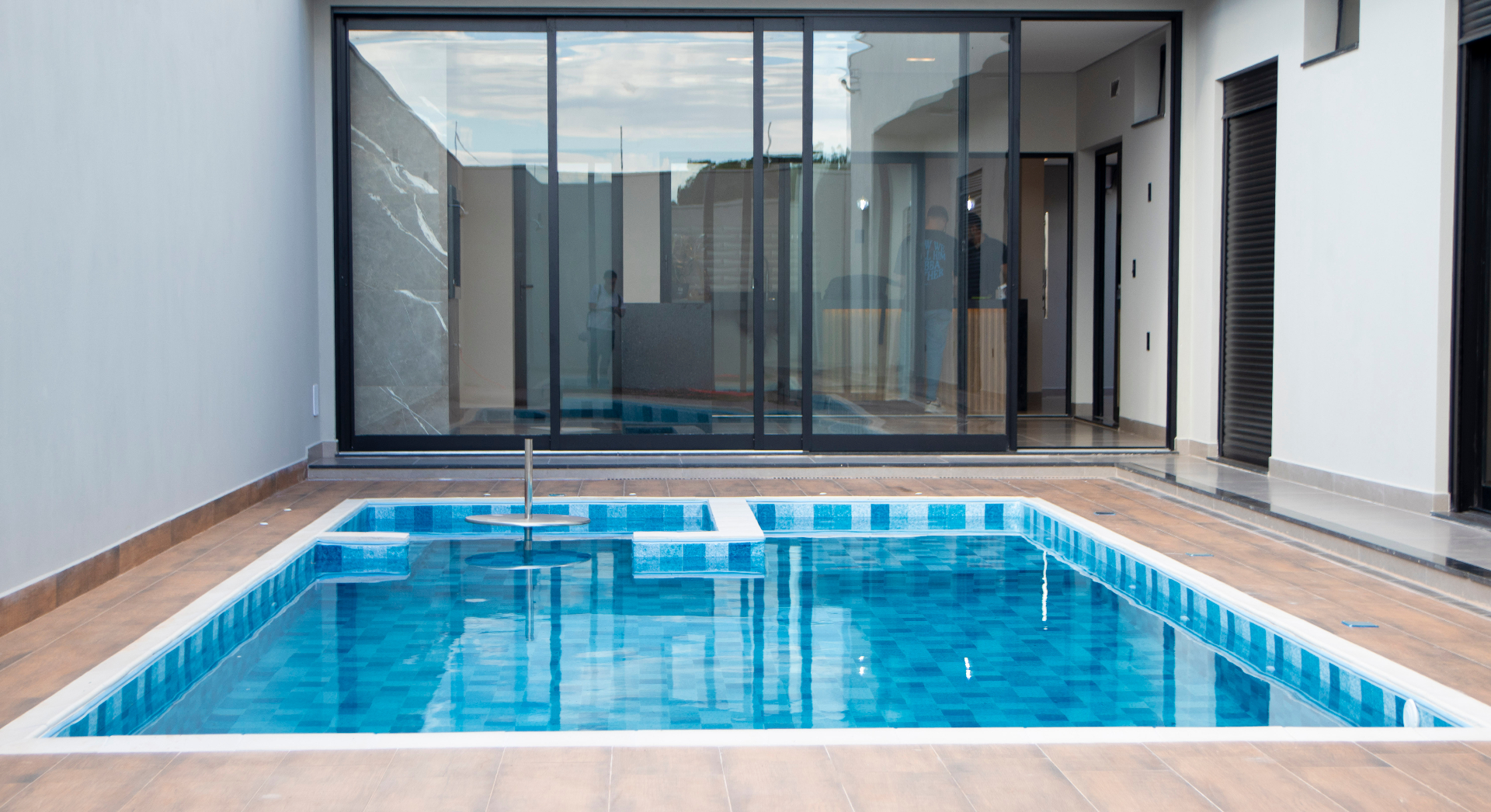 Área de lazer com piscina e fachada envidraçada